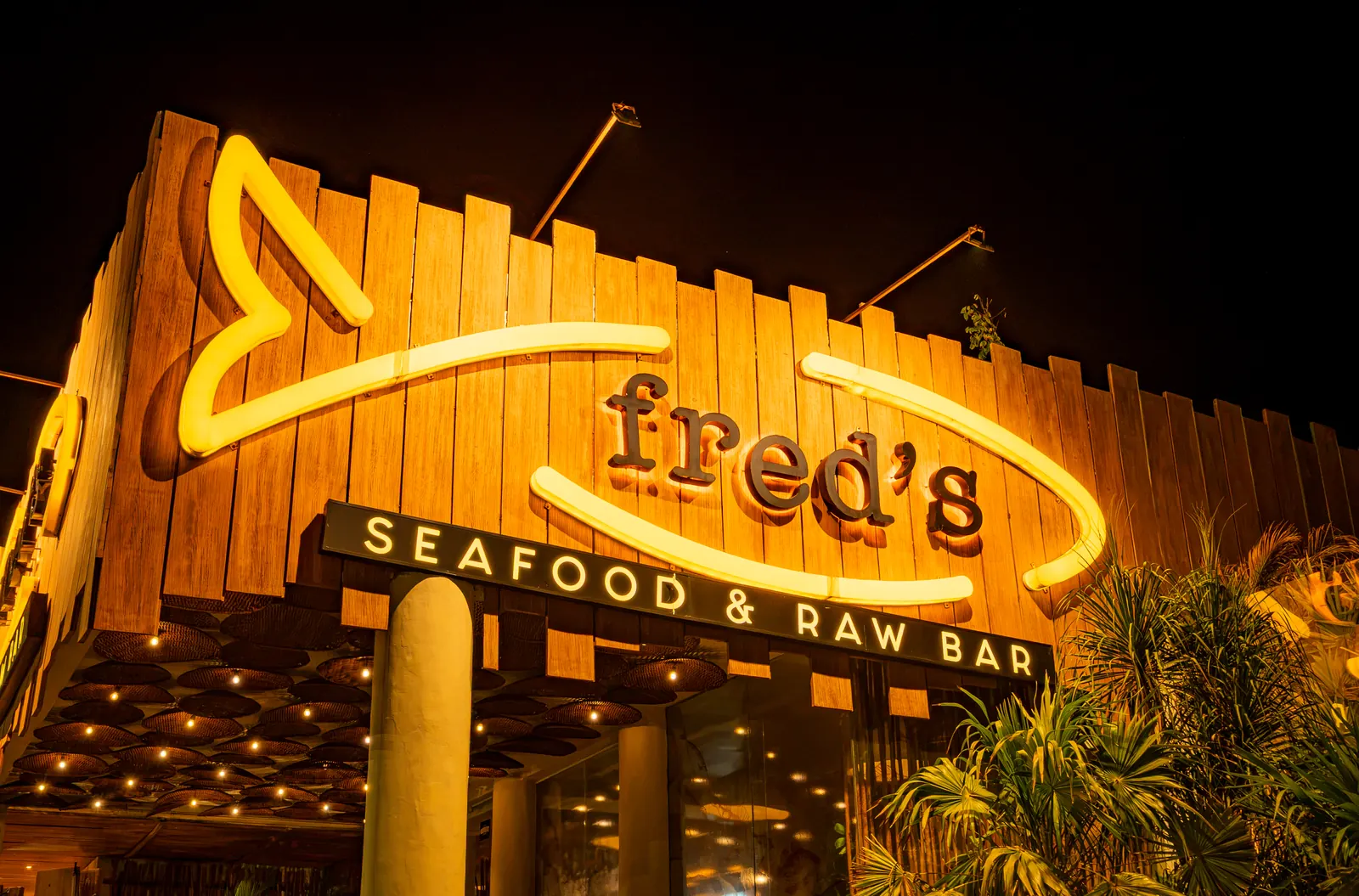 The front of the restaurant at night, with the sign lit